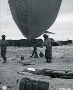 Corporal A. Johnson, from Houston, is assisted by some of his men as they walk a balloon over to a winch, in France on July 24, 1944.