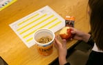 Un estudiante de primer grado en la clase del maestro Lionel Clegg desayuna el primer día de clases en la Primaria Woodlawn en Portland, Oregón, el 27 de agosto del 2024.