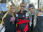(Left to right) Nevina Humphrey, 15, Ellanora Hubbard, 15, and Stella wheeler, 16, left their classes at Lincoln High School in Portland, Ore., to attend a protest at Couch Park, Jan. 20, 2026. Hundreds attended this protest, part of a national day of protest marking one year since Trump returned to the White House.