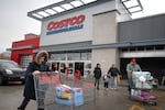 Customers walk in the parking lot outside a Costco store in Chicago on December 2, 2025. Two are pushing large shopping carts.