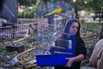 A woman carries a cage with a parrot as she leaves her damaged house following a Russia missile attack in Kyiv, Ukraine, Sunday, July 19, 2026.
