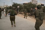 Israeli soldiers move toward a Palestinian man lying wounded on a road after they shot him following a settler attack on Palestinians harvesting olives in the West Bank village of Abu Falah, Friday.