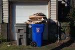 Cardboard packaging sits in a stack on top of a recycling bin outside a garage in Portland. Local and out-of-state businesses that sell packaged products in Oregon are required to pay fees into the state's new recycling system.