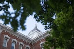 A partial view of an academic building is framed by leafy oak trees.