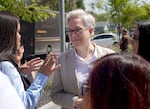 Tina Kotek talks with a woman while in the center of a small crowd