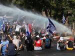 Israeli police use water cannon to disperse demonstrators blocking the road leading to the Knesset, Israel's parliament, during a protest against plans by Prime Minister Benjamin Netanyahu's government to overhaul the judicial system, in Jerusalem, Monday, July 24, 2023.