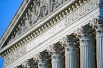 A close up of the top of the Supreme Court building shows the words "Equal justice under the law" carved into the marble of a classical style building.