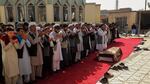 People pray during a funeral ceremony outside in Afghanistan.