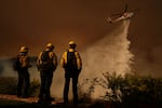 A helicopter drops water on Mandeville Canyon as the Palisades Fire rages Saturday in Los Angeles.