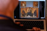 A journalist browses the Messina museum website showing a picture of the Early Renaissance painter Antonello da Messina's artwork where three of the five panels belonging to the Polyptych of San Gregorio and the double-sided panel with the Madonna and the Christ in Pietà, stolen from the Sicilian museum on Aug. 15, in Rome, Sunday, Aug. 16, 2026.