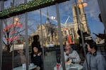 Customers sit inside a restaurant next to France's iconic Notre Dame Cathedral, hours before formally reopening its doors for the first time since a devastating fire nearly destroyed the 861-year-old landmark in 2019, on Saturday, Dec. 7, 2024, in Paris. (AP Photo/Bernat Armangue)