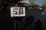 A man displays a placard with portraits of the current and late supreme leaders and the late Revolutionary Guard Gen. Qassem Soleimani at the Islamic Revolution Square in downtown Tehran, Iran, Saturday, July 18, 2026.