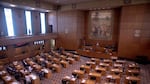 The floor of the Oregon House of Representatives shows desks aligned in rows facing other desks and a podium.