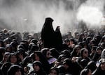 Iranian Shiite Muslims mourn in a ceremony as water is being sprayed for heat management, in Tehran, Iran, Friday, July 4, 2025, ahead of Ashoura, a remembrance of the 7th-century martyrdom of the Prophet Muhammad's grandson, Hussein, who was killed in a battle in Karbala in present-day Iraq. (AP Photo/Vahid Salemi)