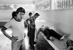 Unidentified men look at two corpses in the city morgue in La Libertad, El Salvador, August 10, 1984. Both victims were shot in the face and showed additional signs of bruising. (Photo by Robert Nickelsberg/Getty Images)