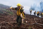 Crew boss Billy Gilbert, in his fifth season as a wildland firefighter, carries two hoses to use on burn piles.