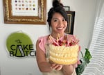 Helen Hồng Nguyễn smiles and shows a cake that she decorated in her home studio.