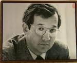 A man with glasses stares at the camera as he gets his picture taken.