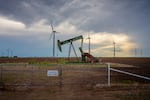 An oil pumpjack is seen near a field of wind turbines in Nolan, Texas.