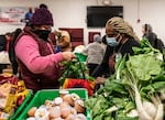 Team members at the No Limits Food Pantry distribution center pack recipient bags with fresh produce and can goods.