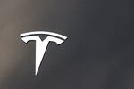 The Tesla company logo is seen on the hood of a vehicle.