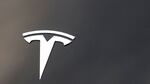 The Tesla company logo is seen on the hood of a vehicle.
