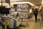A person walks down a crowded hallway filled with medical equipment in the emergency room.