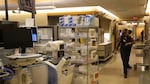 A person walks down a crowded hallway filled with medical equipment in the emergency room.
