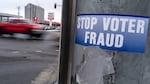 A sticker on a lamp post warns of voter fraud on Nov. 7, 2022, in Anchorage, Alaska. Alaska is part of a bipartisan compact of more than 30 states that shares voting data.