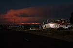 In the this long exposure, houses and farms sit in a Level 2 “Be Set” evacuation zone in Madras, Ore., as the Bench Fire glows in the distance on July 27, 2026.