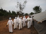 A burial team in Liberia awaits decontamination after performing "safe burials" for people who died of Ebola during the 2014-15 outbreak. Strains of the virus are harbored by bats and primates. A new study looks at how human activity affects the transmission of infectious diseases like Ebola.