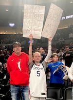 A fan of Connecticut basketball star Paige Bueckers sports "Paige Bueckers' Mini Me" and "Paige Bueckers is Miss March" signs at the Moda Center on Saturday, Mar. 30, 2024. The Connecticut Huskies beat Duke to advance to the Elite 8 in Portland.
