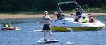 A boat tows people in a tube near a stand-up paddleboarder in violation of new rules that prohibit towed water sports on a crowded stretch of the Willamette River south of Portland's Hawthorne Bridge.