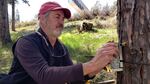 Bureau of Land Management ecologist Charlie Schelz checks a trail camera near I-5 to collect information about future wildlife crossing locations.