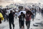 Palestinians carry bags and folded cardboard boxes as they return from a food distribution point run by the U.S. and Israeli-backed Gaza Humanitarian Foundation group, near the Netsarim corridor in the central Gaza Strip on Saturday.