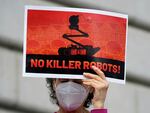 A woman holds up a sign while taking part in a demonstration about the use of robots by the San Francisco Police Department outside of City Hall in San Francisco on Monday.