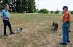 Dean Suhr, left, talks with Jim Driscoll as Suhr walks his son's dogs through Oppenlander Field in West Linn, Ore., on July 17, 2026.