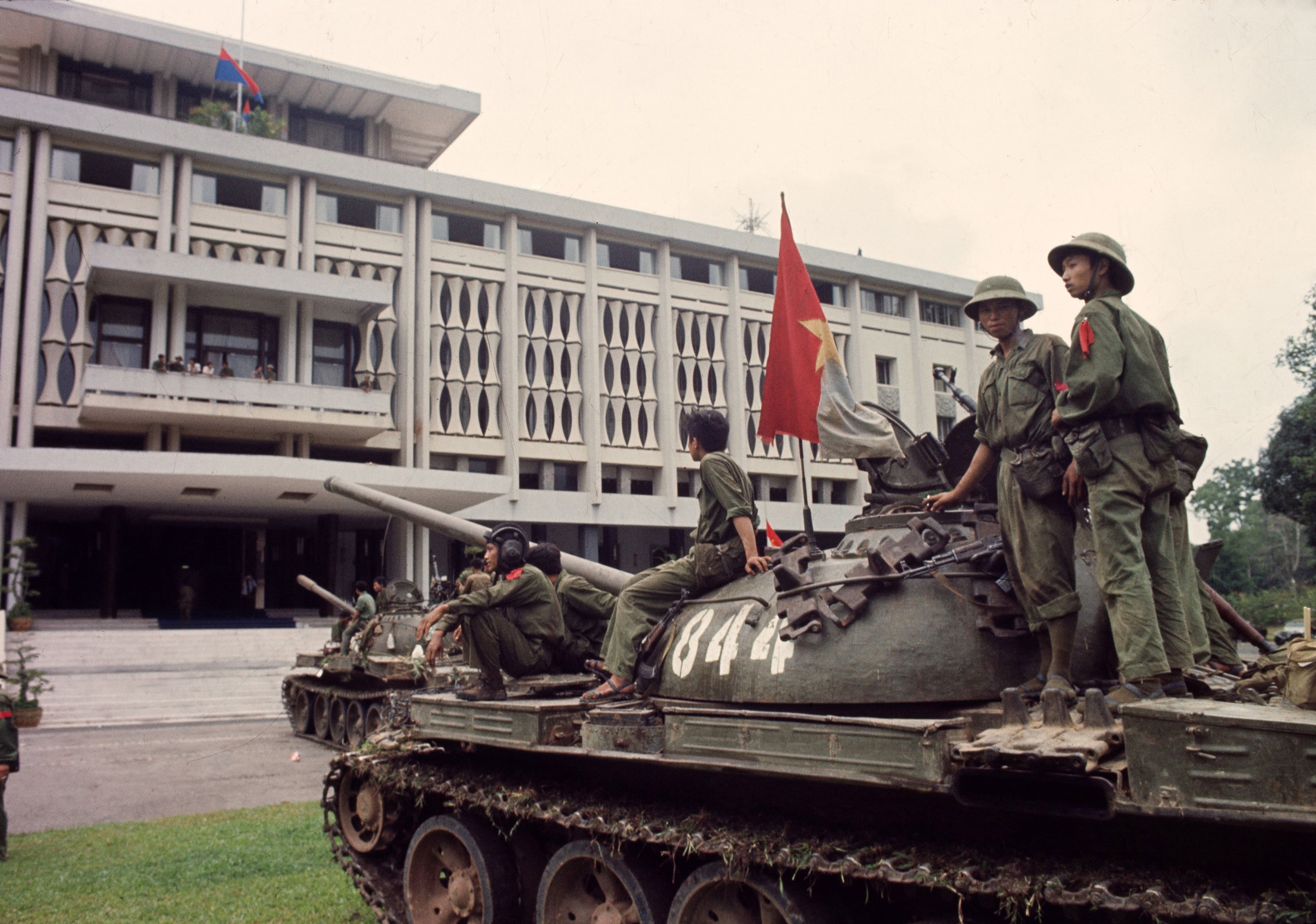 Victorious North Vietnamese troops on tanks take up positions outside Independence Palace in Saigon on April 30, 1975, the day the South Vietnamese government surrendered, ending the Vietnam War. Communist flags fly from the palace and the tank.