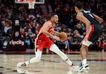 New Orleans Pelicans guard CJ McCollum, left, dribbles around Portland Trail Blazers forward Kris Murray during the second half of an NBA basketball game in Portland, Ore., Tuesday, April 9, 2024.