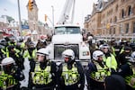 Police hang off a truck as authorities work to end a protest against COVID-19 measures in Ottawa on Feb. 19, 2022.