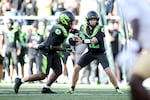 Oregon quarterback Brock Thomas (12) hands off the ball to running back Jordon Davison (0) during the second half of an NCAA college football game against UCLA, Saturday, Oct. 10, 2026, in Eugene, Ore.