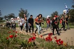 Relatives of the hostages who remain in captivity in Gaza and their supporters pass by red anemone flowers as they begin a four-day march from the site of the Hamas attack on the Nova music festival in Re'im, Israel, to Jerusalem on Feb. 28.