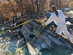Archaeologist Tyler Davis (right) and Valerie Linfoot's husband, Chuck (left), lift a piece of metal roofing off of where they suspect the cremated remains might have fallen in the fire.