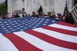 A group of Proud Boys unfurl a large American flag in front of the Oregon state Capitol during a rally to reopen Oregon in Salem on Saturday, May 2, 2020.