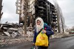 An elderly woman walks by an apartment building destroyed in the Russian shelling in Borodyanka, Ukraine, Wednesday, April 6, 2022.