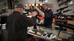 Jared Treadway, 26, a sales associate at Northwest Armory in Portland, shows a customer an AR-15 rifle Tuesday in the store's showroom.