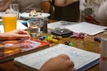 Players at set up for a game of Dungeons & Dragons with dice sets, player sheets and player handbooks. The game uses various dice rolls to move the story forward and determine if an action succeeds or fails.