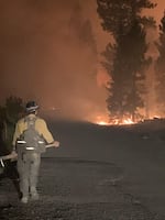 A firefighter walks towards a distance blaze.