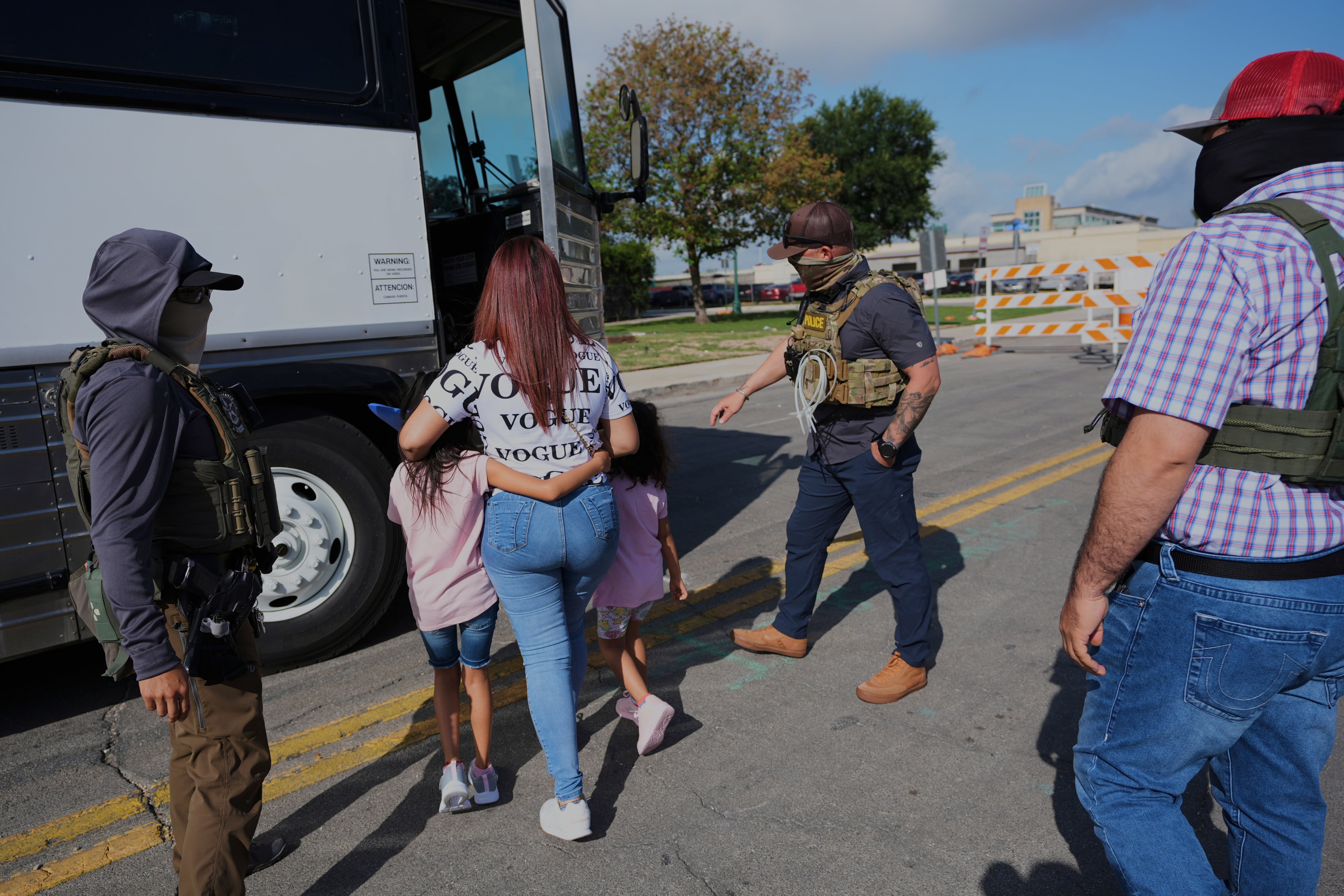 A woman from Peru and her children are detained and escorted to a bus by federal agents following an appearance at immigration court on June 23, 2025, in San Antonio.
