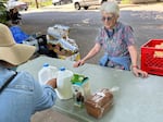 Urban Gleaners volunteer Carey Booth lays out milk and bread at the Free Food Market in Lents Park on May 25, 2023. 